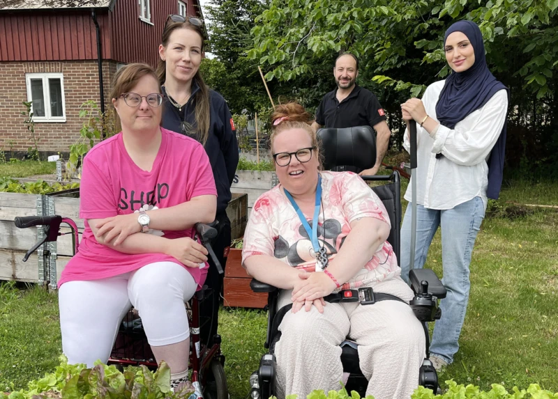 En grupp personer tittar in i kameran och ler.