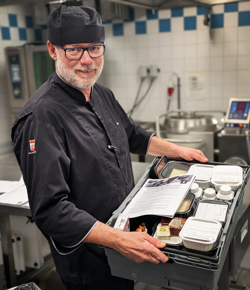 Medelålders man bär en låda full med mat och lagade rätter