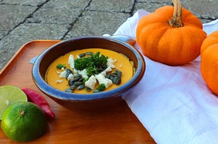 En tallrik pumpasoppa stående på enn träbricka