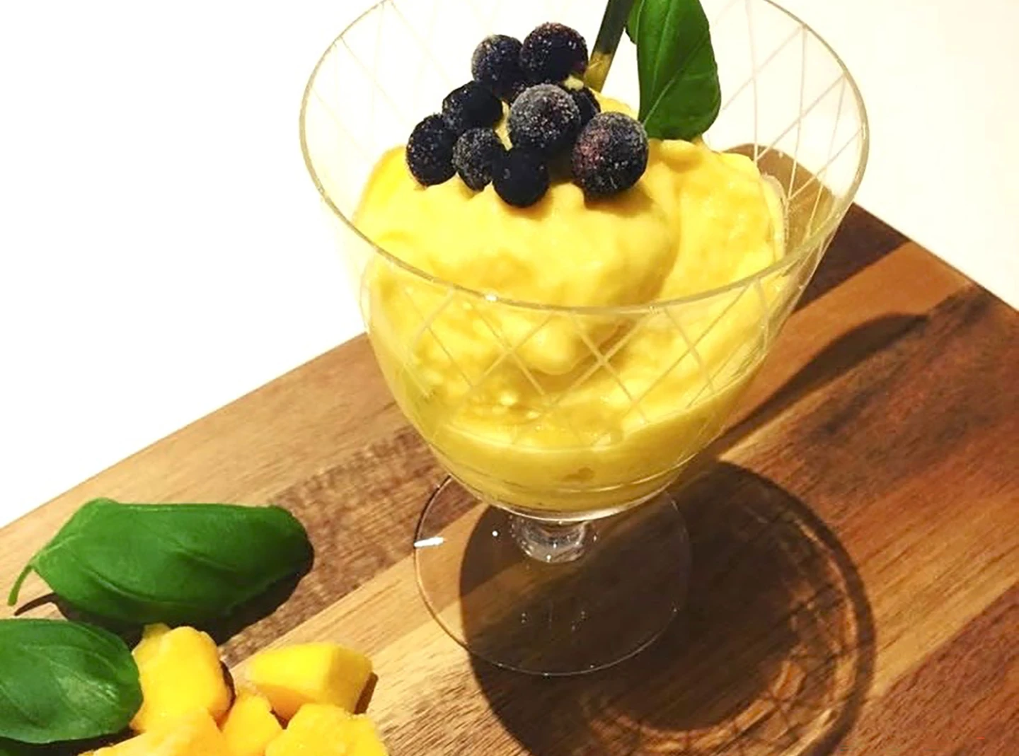 Ett glas med mangoglass på en träbricka...