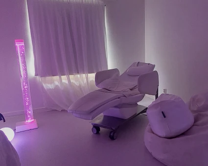 En massagestol i ett mörklagt rum med lila belysning