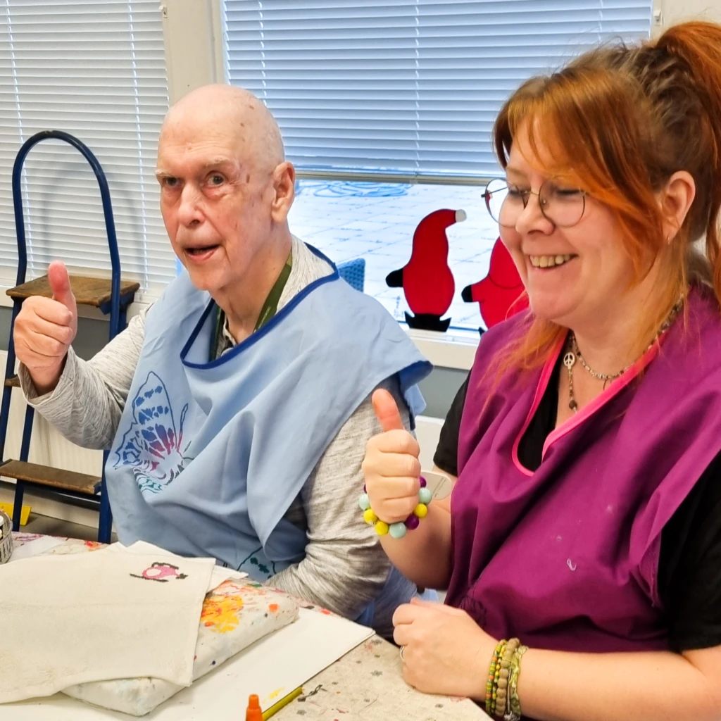 En man och en kvinna tittar in i kameran, ler och ger tummen upp.