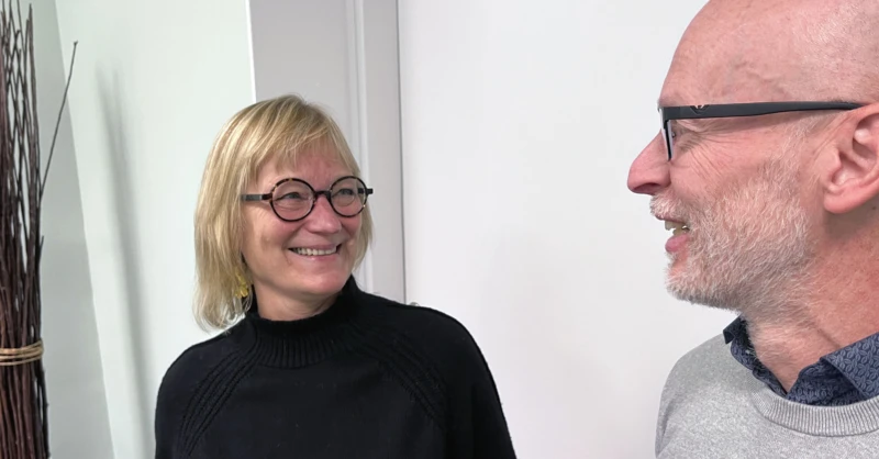 Medelålders man och kvinna i glasögon står och samtalar