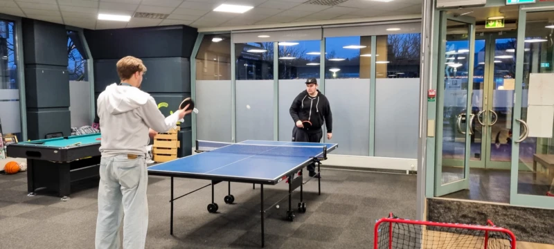 Två killar spelar pingis på ett pingisbord.