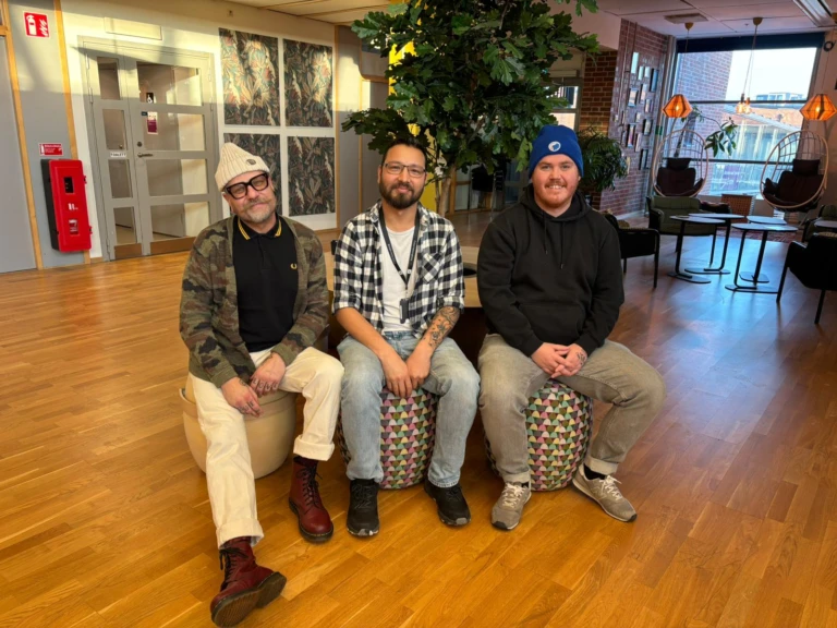 Tre killar som arbetar med anpassad mötesplats ler in i kameran