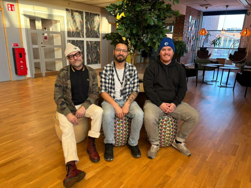 Tre killar som arbetar med anpassad mötesplats ler in i kameran