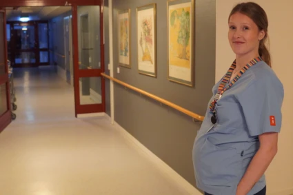 Kvinna tittar in i kameran samtidigt som hon är på sitt jobb