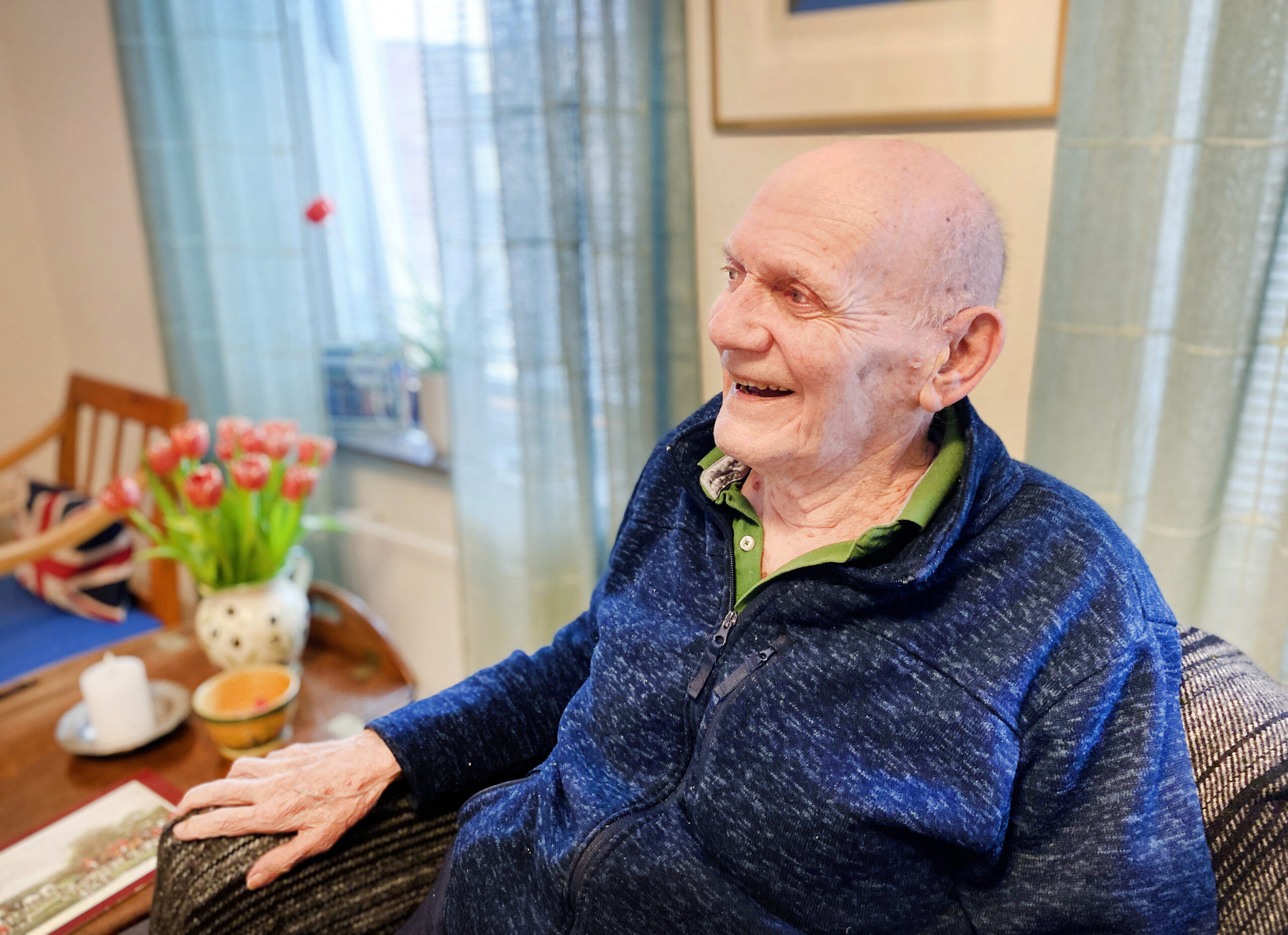 En man sitter i en fåtölj och skrattar.