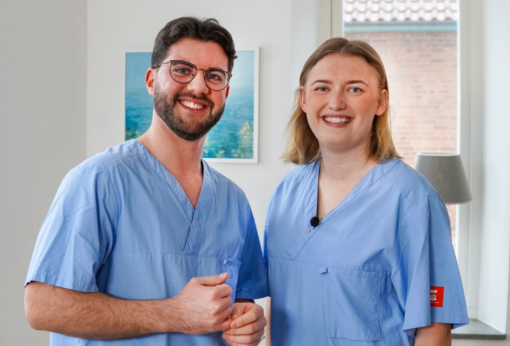 Två personer ler och tittar in i kameran.