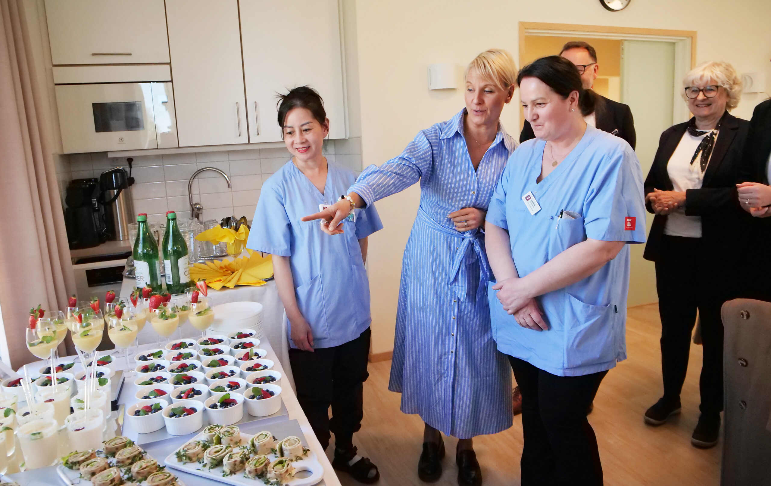 En grupp människor står vid ett dukat bord.