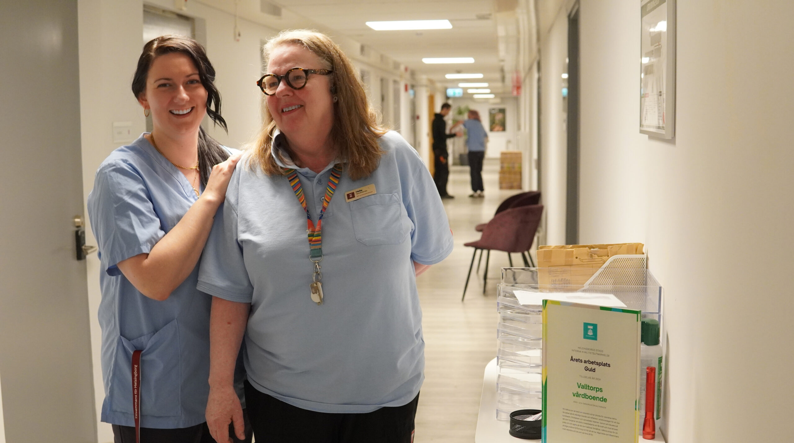 Två glada kvinnor i en korridor på sitt arbete
