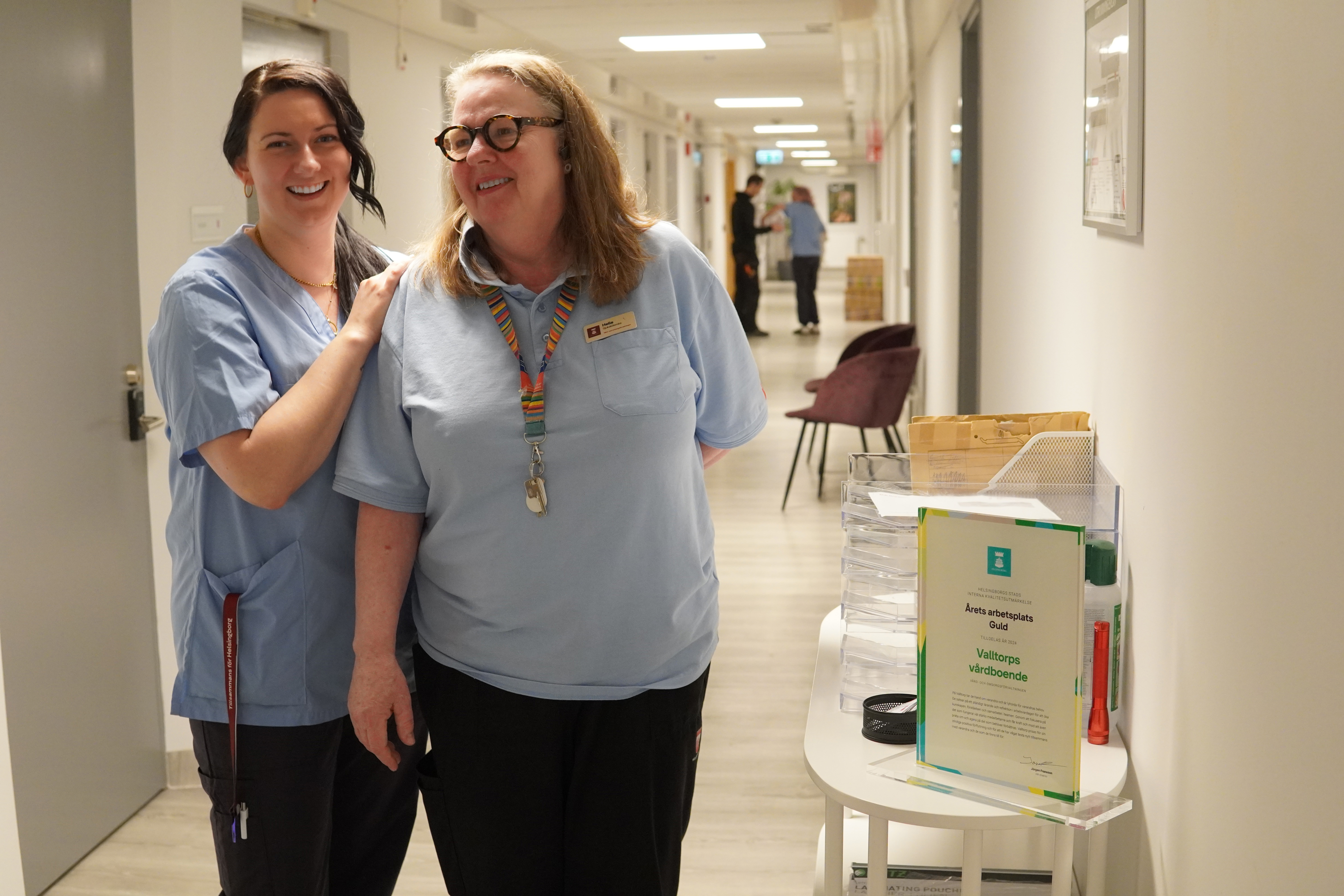 Två glada kvinnor i en korridor på sitt arbete