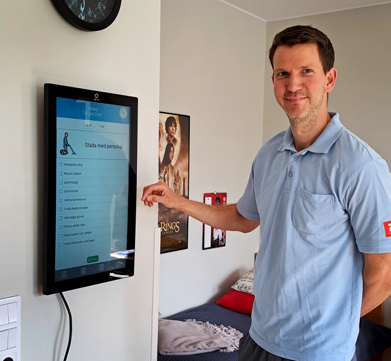 En man står och pekar på en digital skärm som sitter på väggen