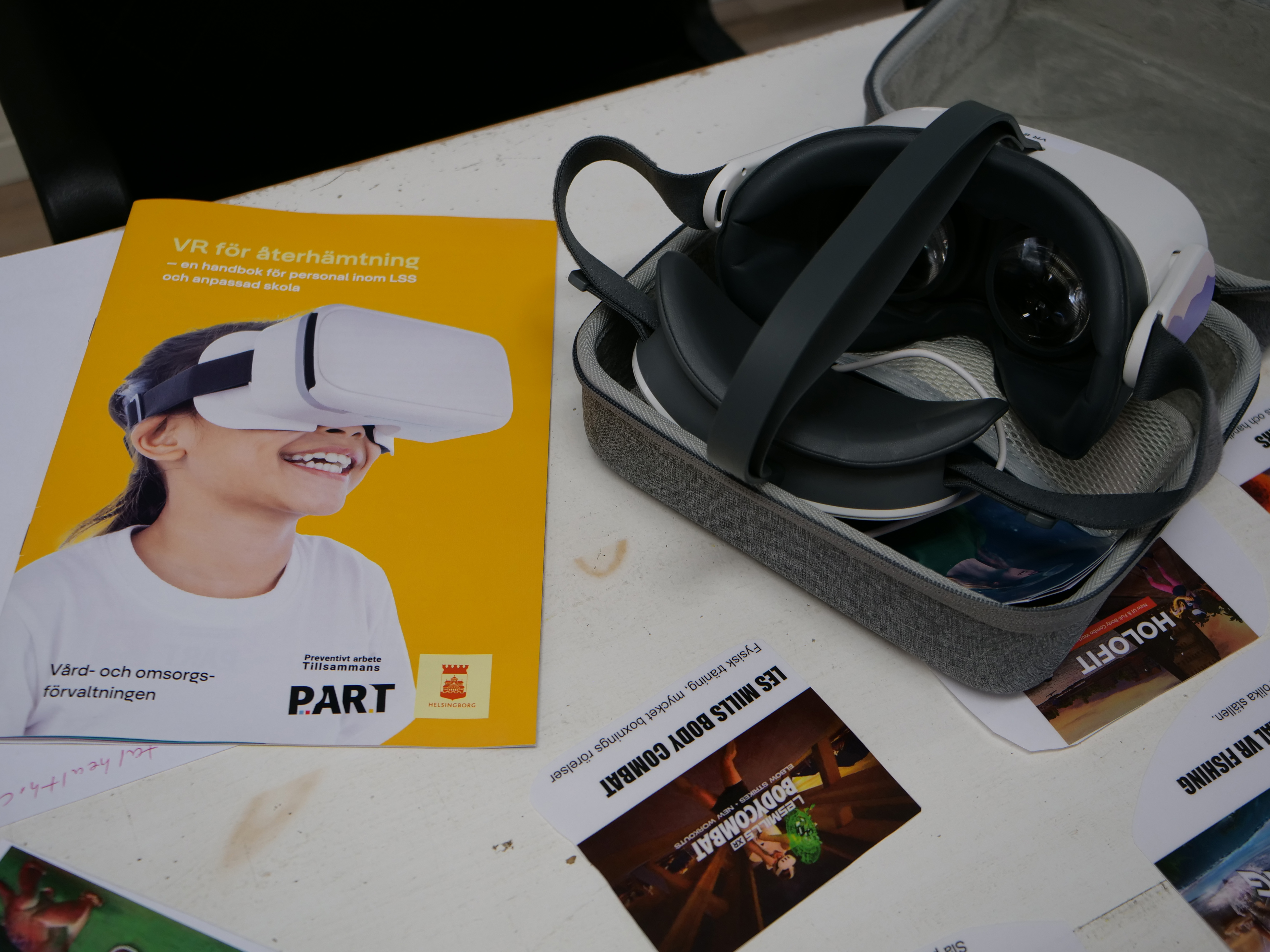 Broschyr, VR-glasögon och laminerade lappar som visar vilka VR-spel som finns att välja på.