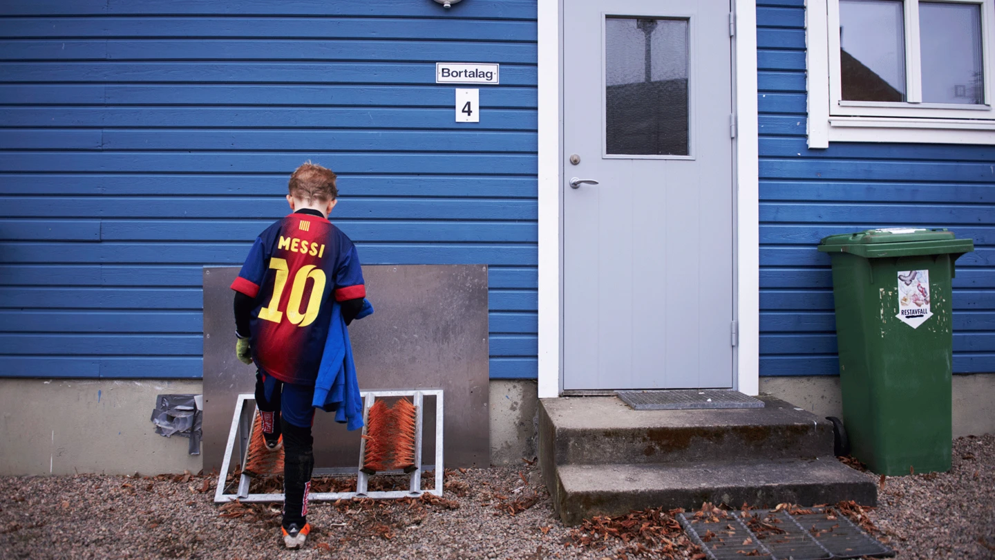 Pojke med FC Barcelona-tröja framför klubbhus. Foto: Anna Bank