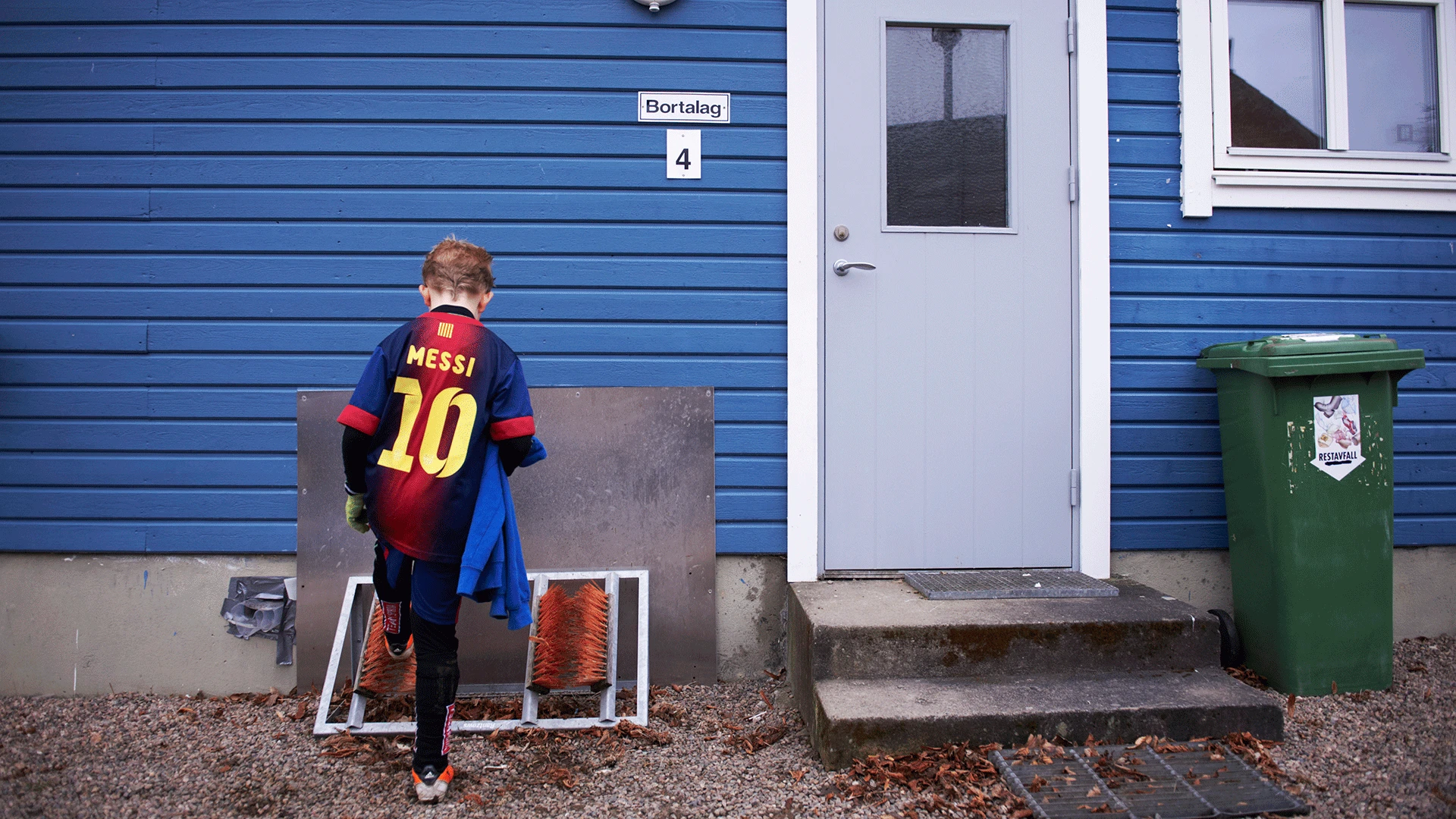 Pojke med FC Barcelona-tröja framför klubbhus. Foto: Anna Bank