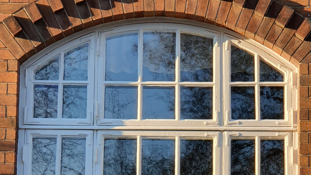 Gamla fina fönster på en brun tegelbyggnad.