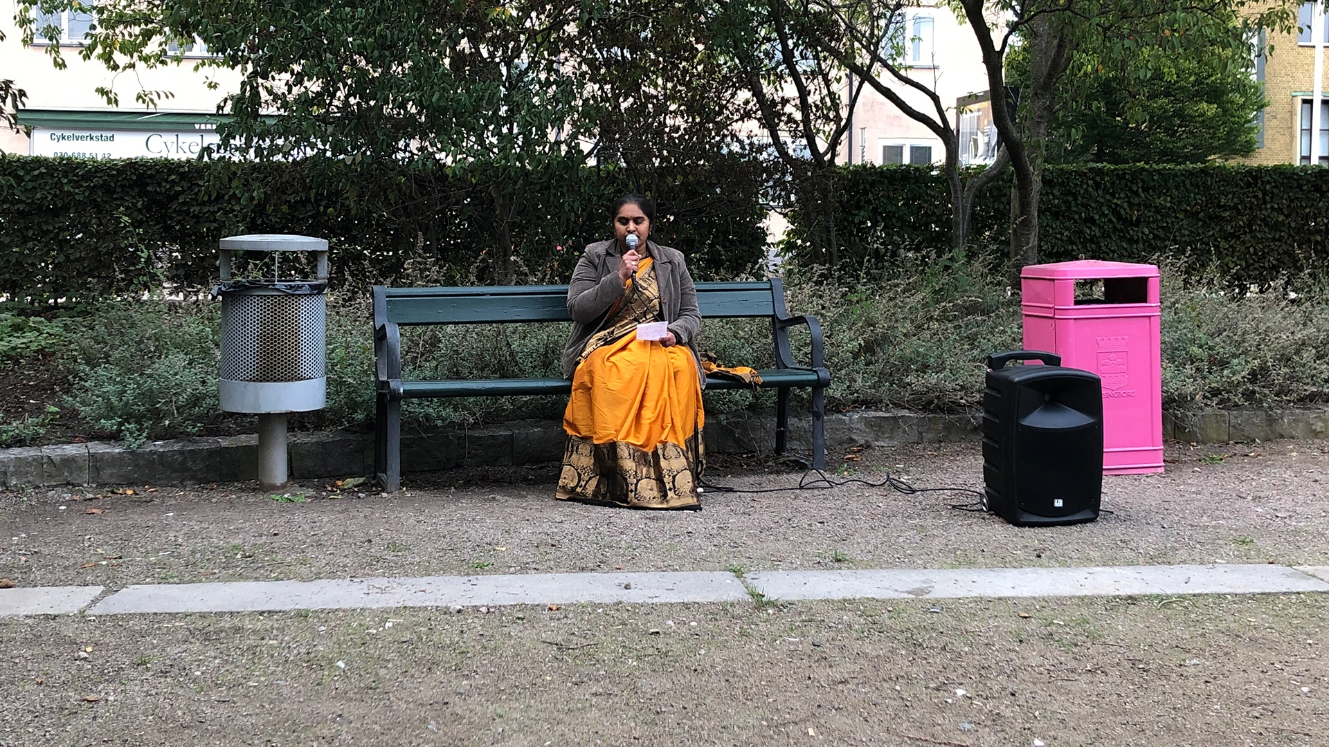 Indira Seshukumar sjunger indiska sånger på en bänk på Furutorpsplatsen.