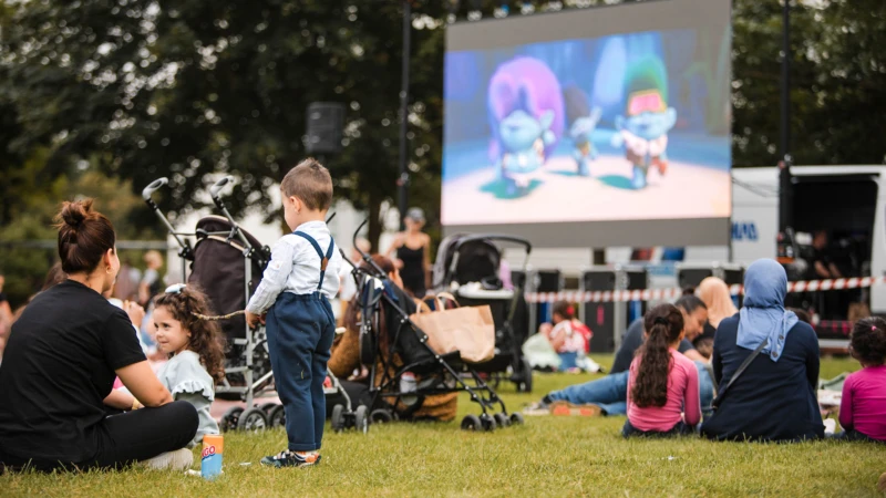 Barn och vuxna som ser på film i gröngräset på Furutorpsplatsen