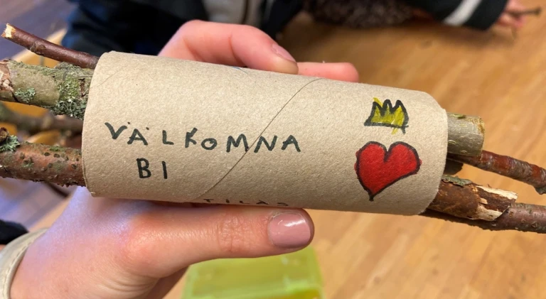 En tom toalettrulle med pinnar i och texten "Välkomna bi"-