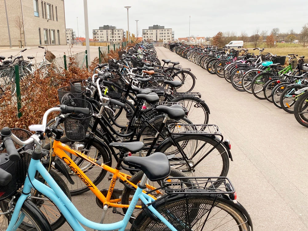 Cyklar i en lång rad i ett cykelställ på en skolgård.