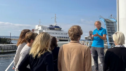 En pedagog från Miljöverkstadens står på Varvsbron och presenterar något för en grupp.