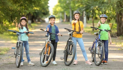Fyra barn står vid cyklar och gör tummen upp.