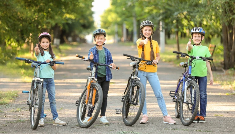 Fyra barn står vid cyklar och gör tummen upp.