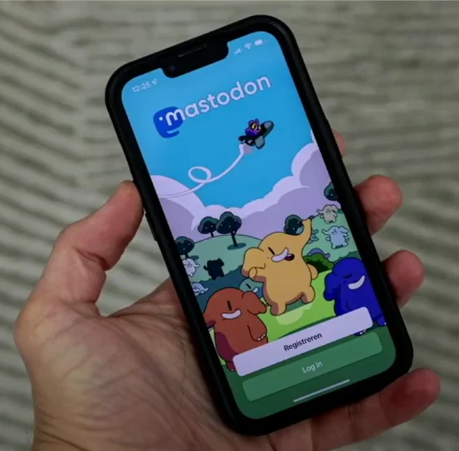 En hand håller en mobiltelefon som visar inloggningssidan till Mastodon