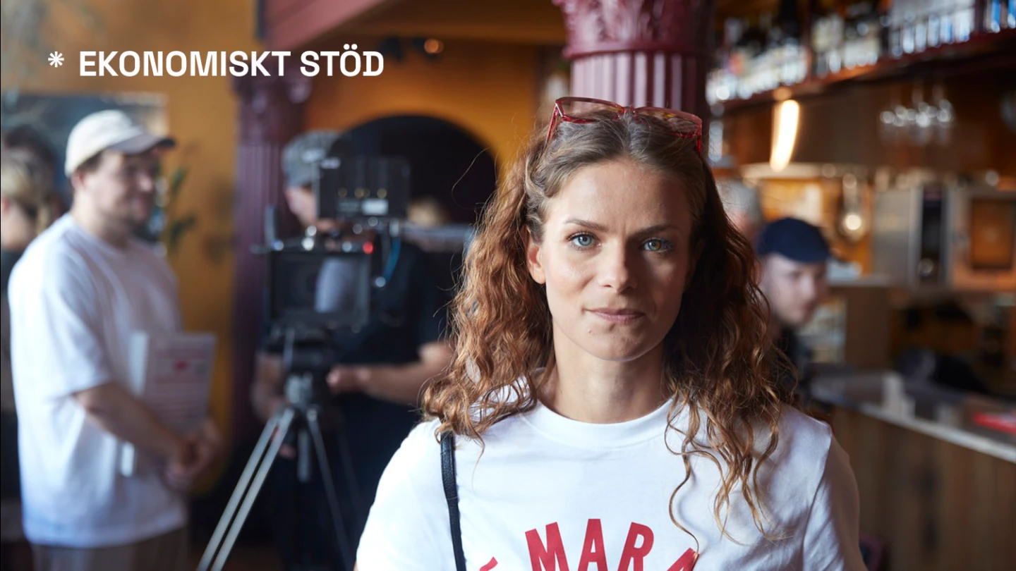 Kvinna tittar mot kameran och i bakgrunden pågår förberedelser för en filminspelning. Text i bild: Ekonomiskt stöd