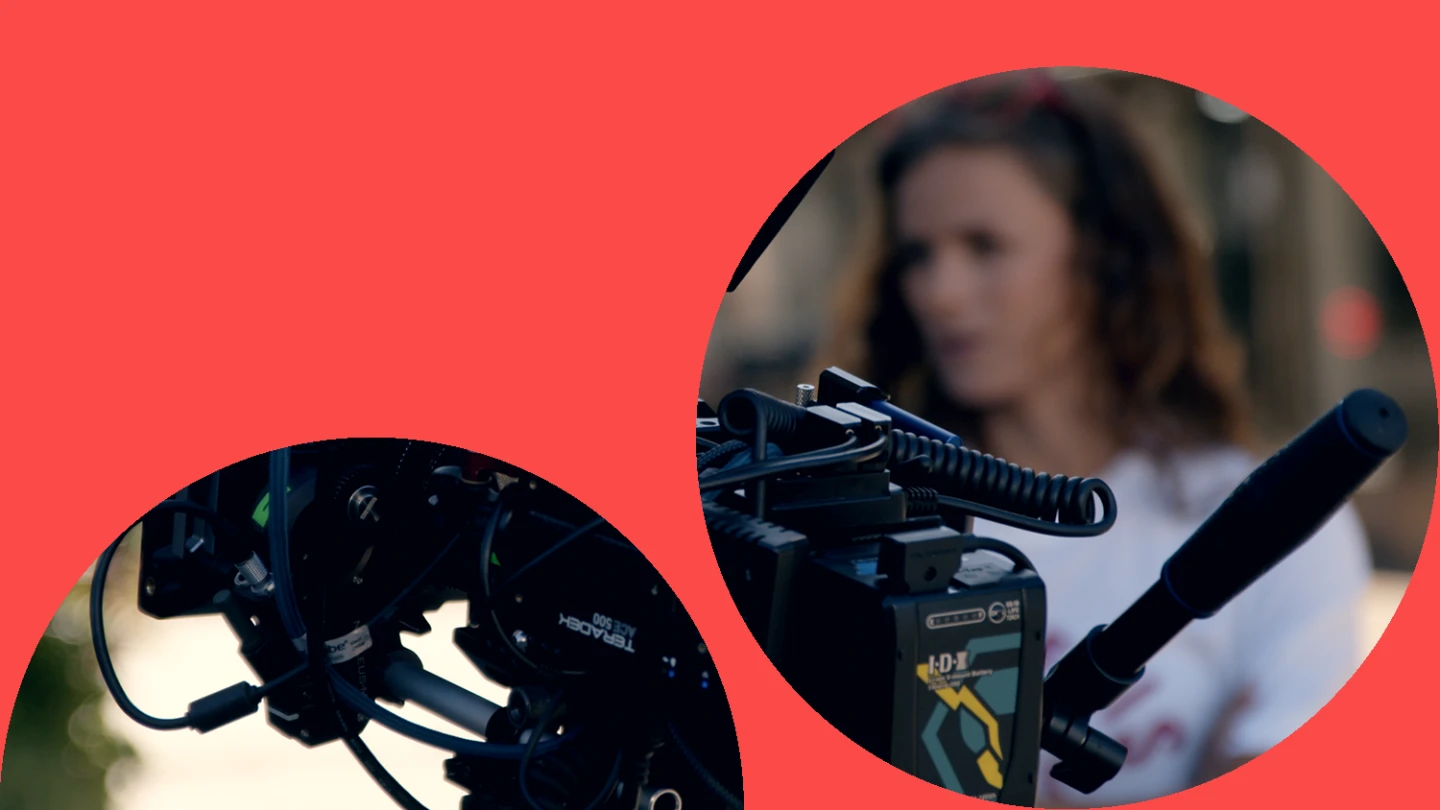 Filmkamera och i bakgrunden syns en kvinna ur fokus.
