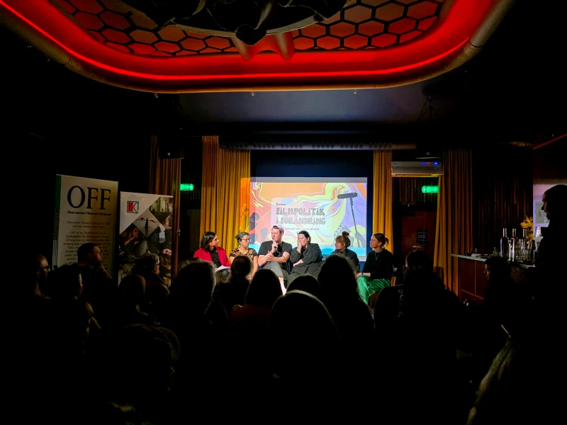 Panelsamtal på scen med publik i salongen.