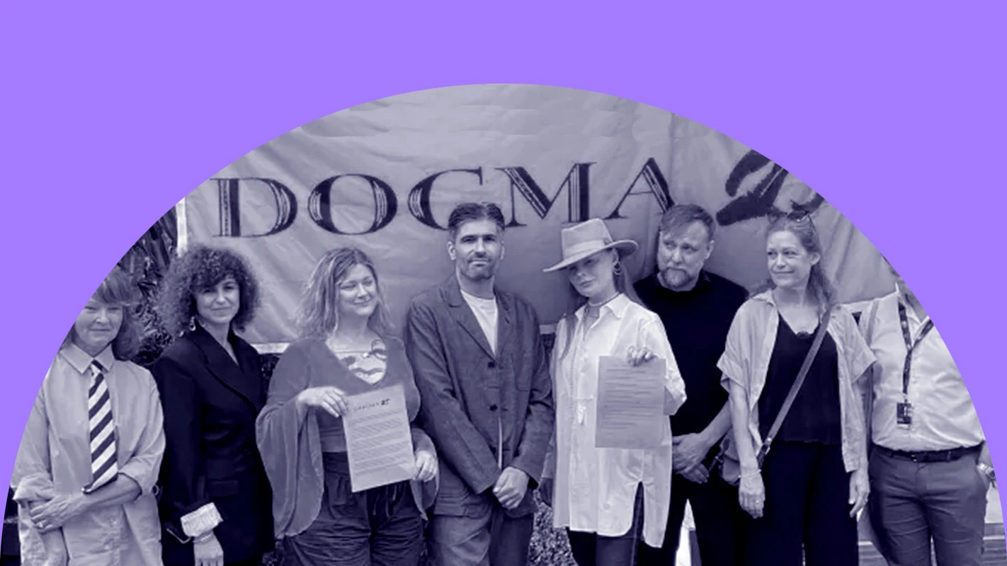 En grupp personer står framför en banderoll med texten Dogma 25.