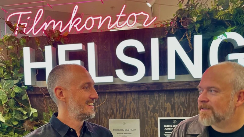 Två män står framför en neonskylt med texten "Filmkontor"