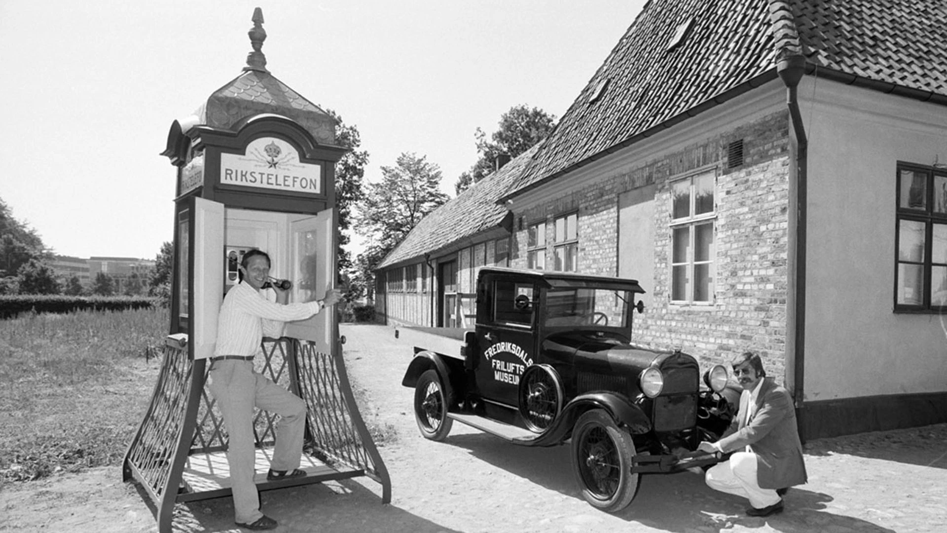 svartvit bild från Fredriksdal med telefonkiosken och en äldre bil