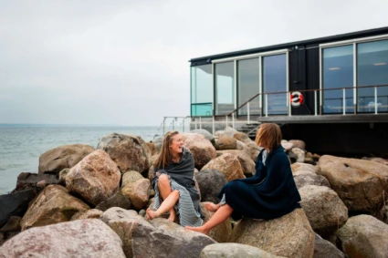 två kvinnor bland stenar på stranden