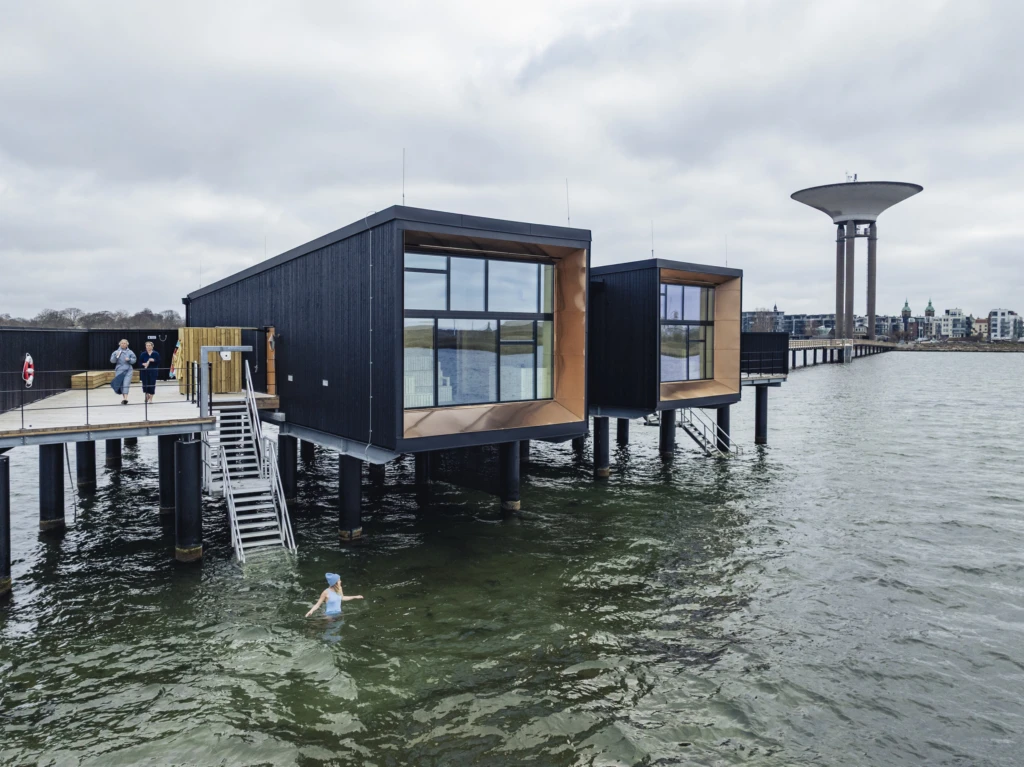 Landskrona kallbadhus sett från havet. En person är i vattnet och badar.