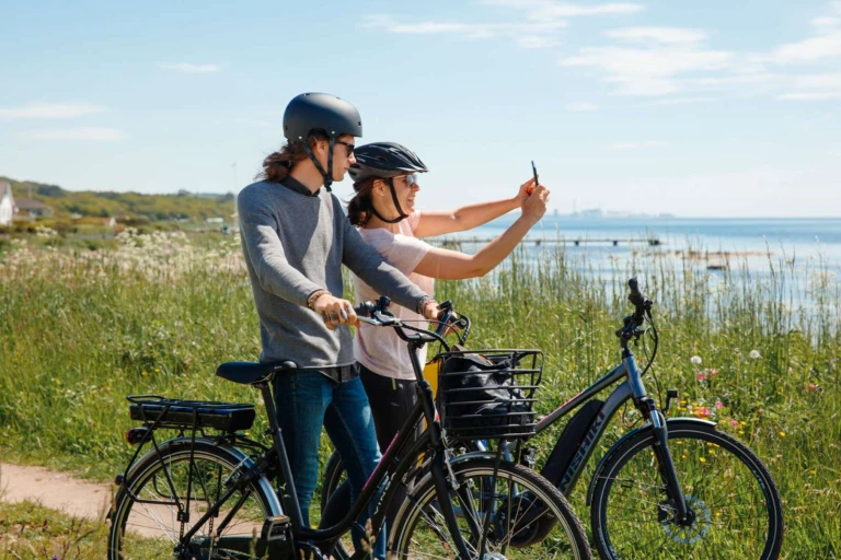 två cyklister stannar för en selfie vid havet