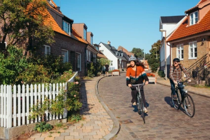 2 personer cyklar på en gata i en by.