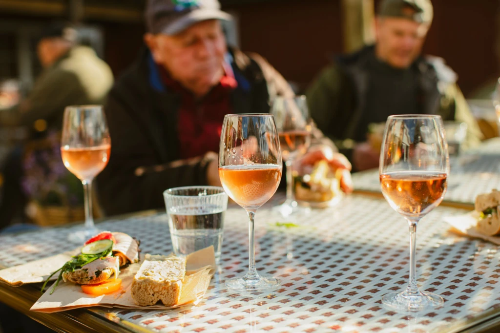 några personer vid ett bord på restaurang. Rosé i glasen rutig duk.