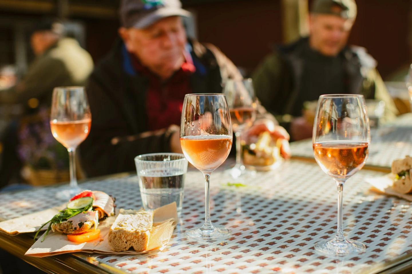 några personer vid ett bord på restaurang. Rosé i glasen rutig duk.