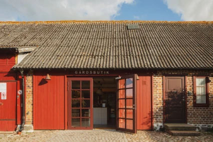 fasaden till Kullabergs vingårds gårdsbutik. Öppen dörr. Röda detaljer
