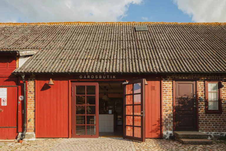 fasaden till Kullabergs vingårds gårdsbutik. Öppen dörr. Röda detaljer